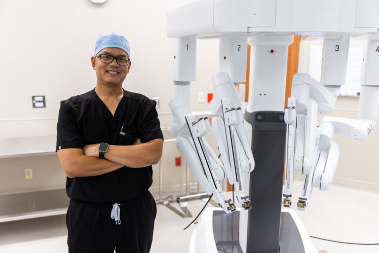 A bariatric doctor near Austin stands next to the da Vinci surgical system.